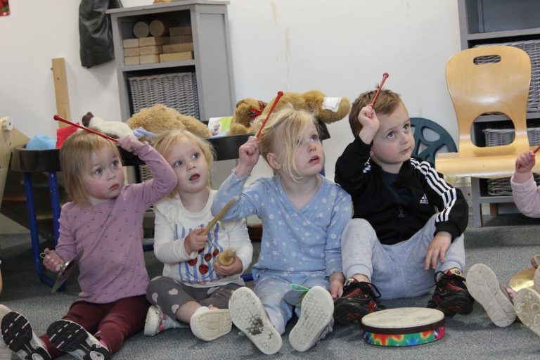 Children holding beaters in the air during a music session