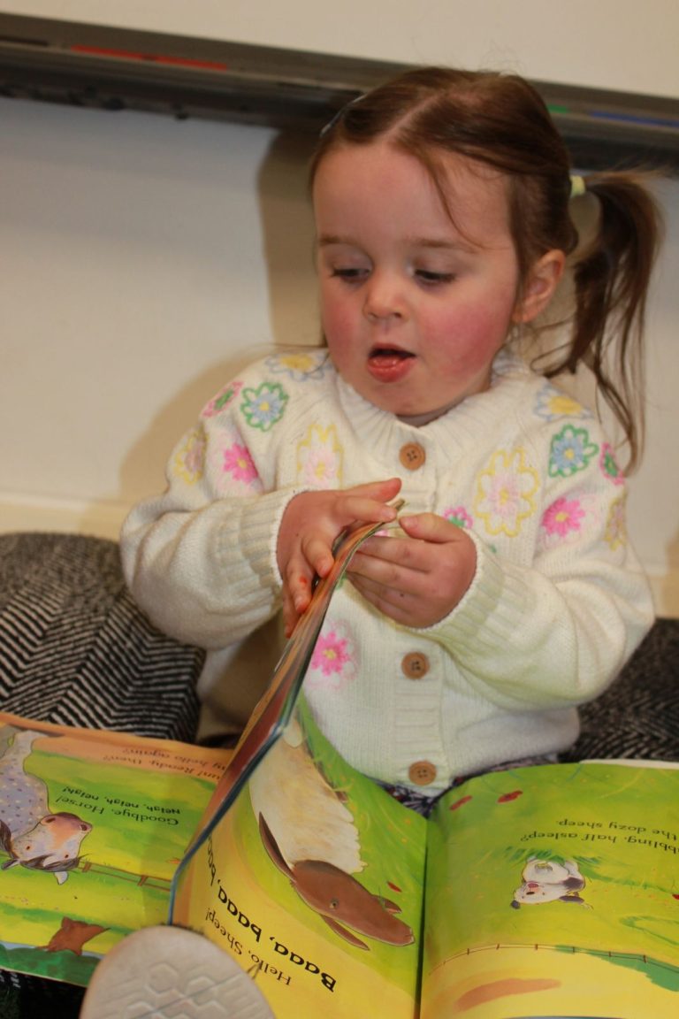 A toddler turning the pages of a picture book