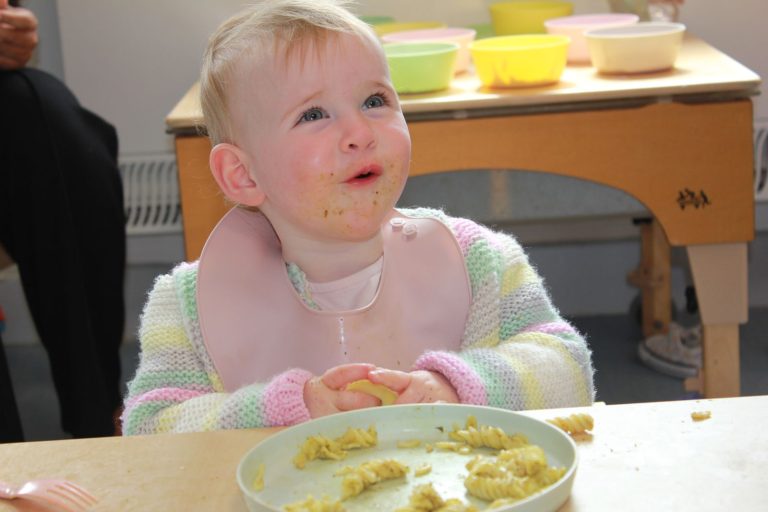 A baby smiling at lunchtime