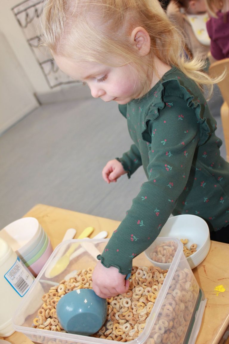 A child scooping cereal into a bowl