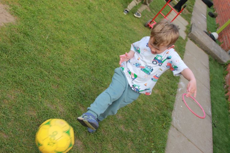 A child kicking a football on the grass