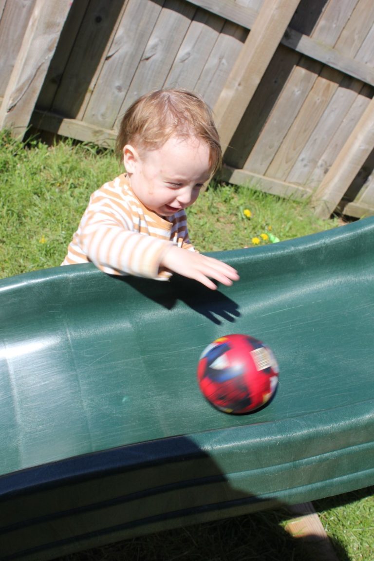 A child rolling a ball down the slide
