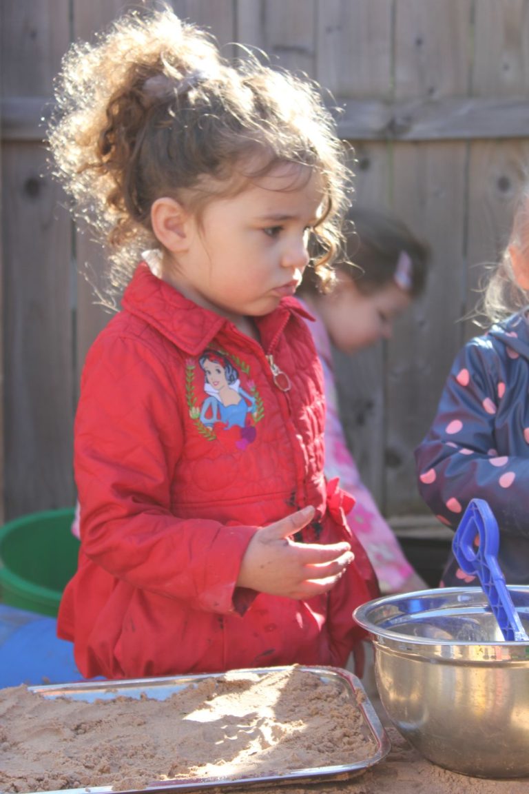 A child playing in the sand tray outdoors