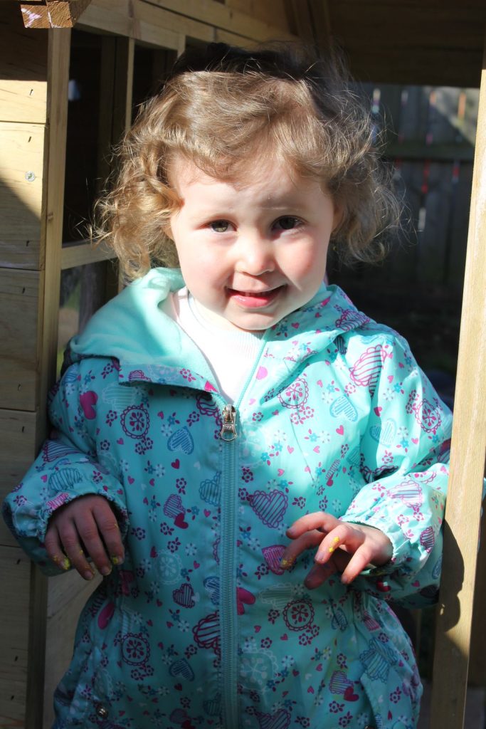 A smiling child in the wooden playhouse