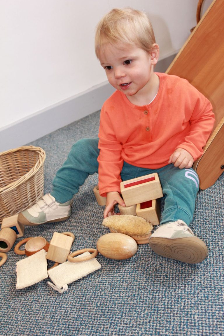 A baby playing with wooden blocks and natural objects