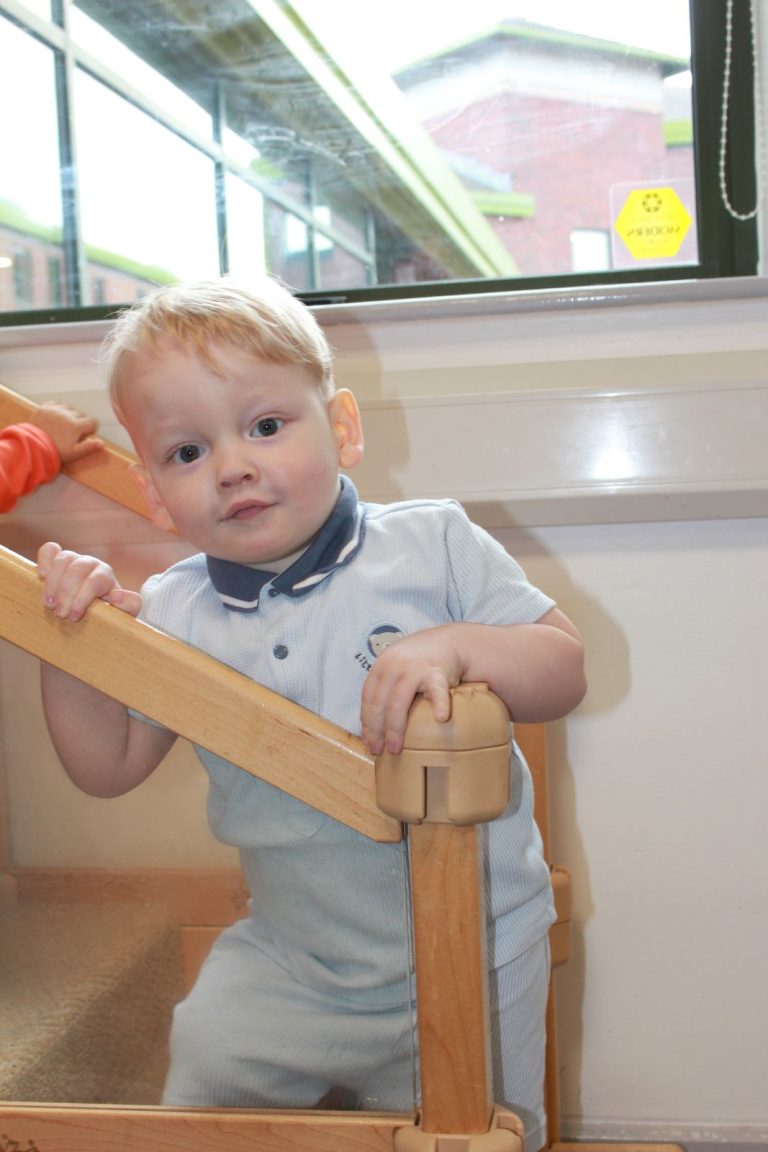 A baby pulling up to stand at a wooden gate