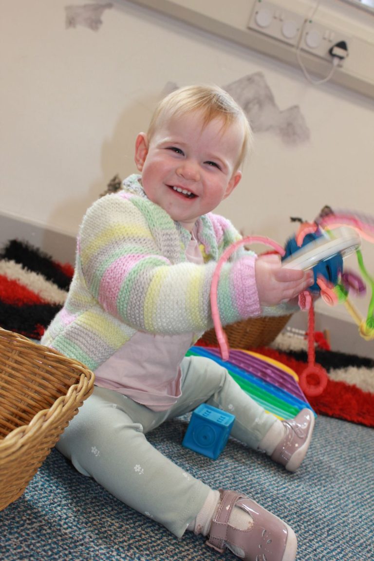 A baby smiling with a sensory toy