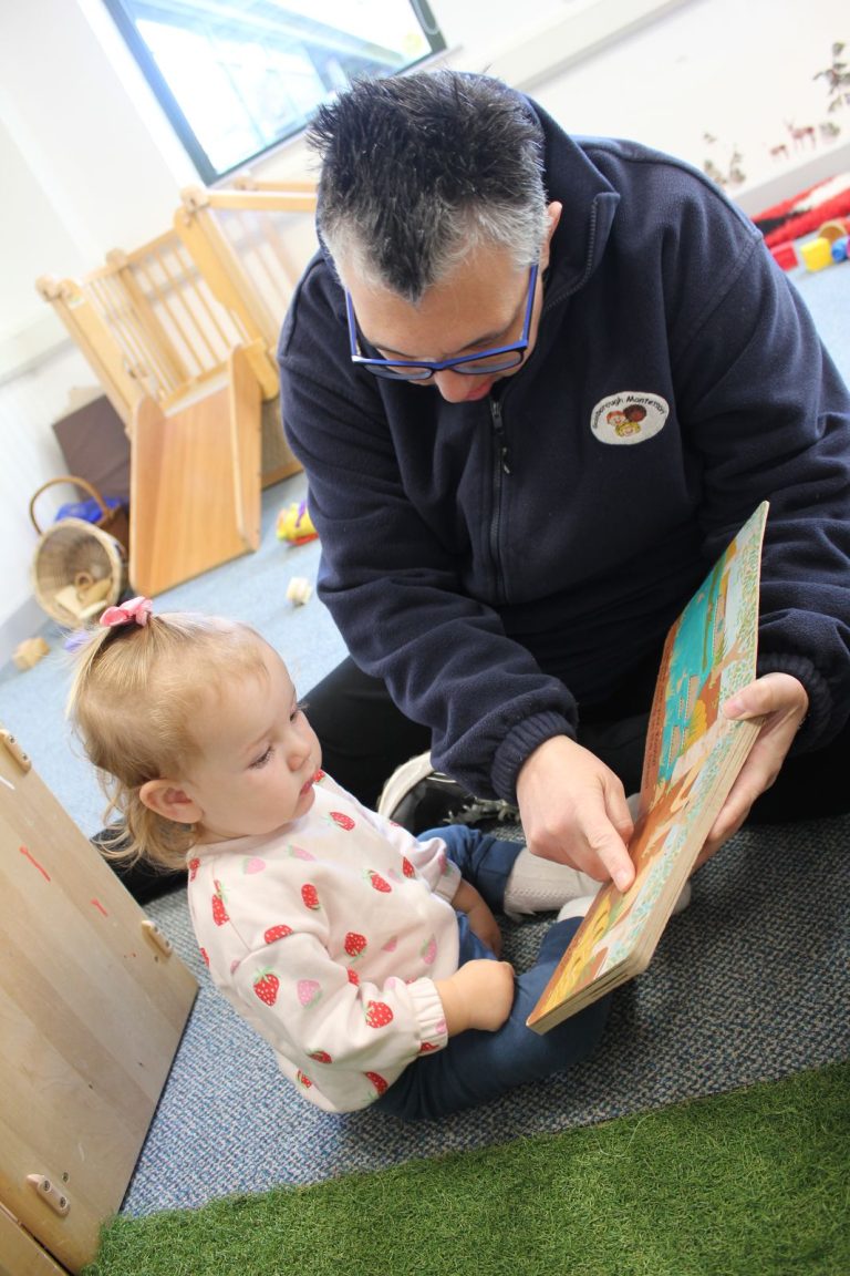 An early years educator reading a book with a baby