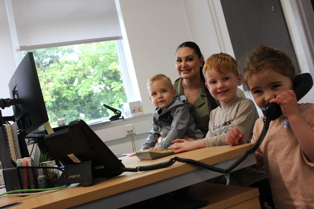 An early years educator with children at the nursery office desk